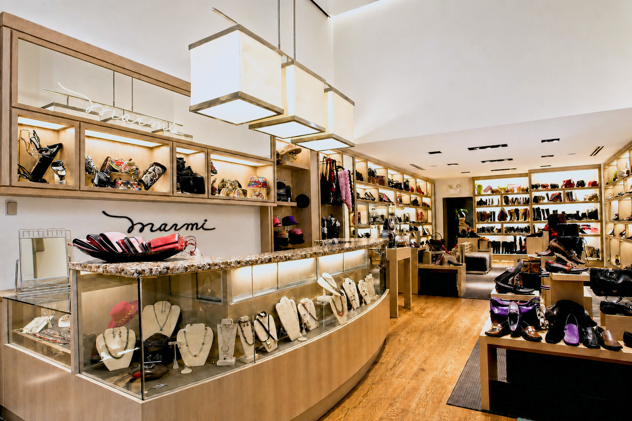 Marmi boutique interior with curved jewelry counter and lit shoe walls